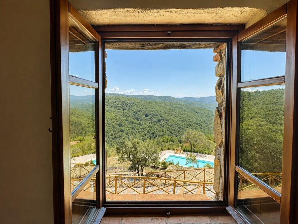 Finestra aperta con vista panoramica sulla piscina e sulle colline nell'appartamento Il belvedere, Borgo Braila, Umbria
