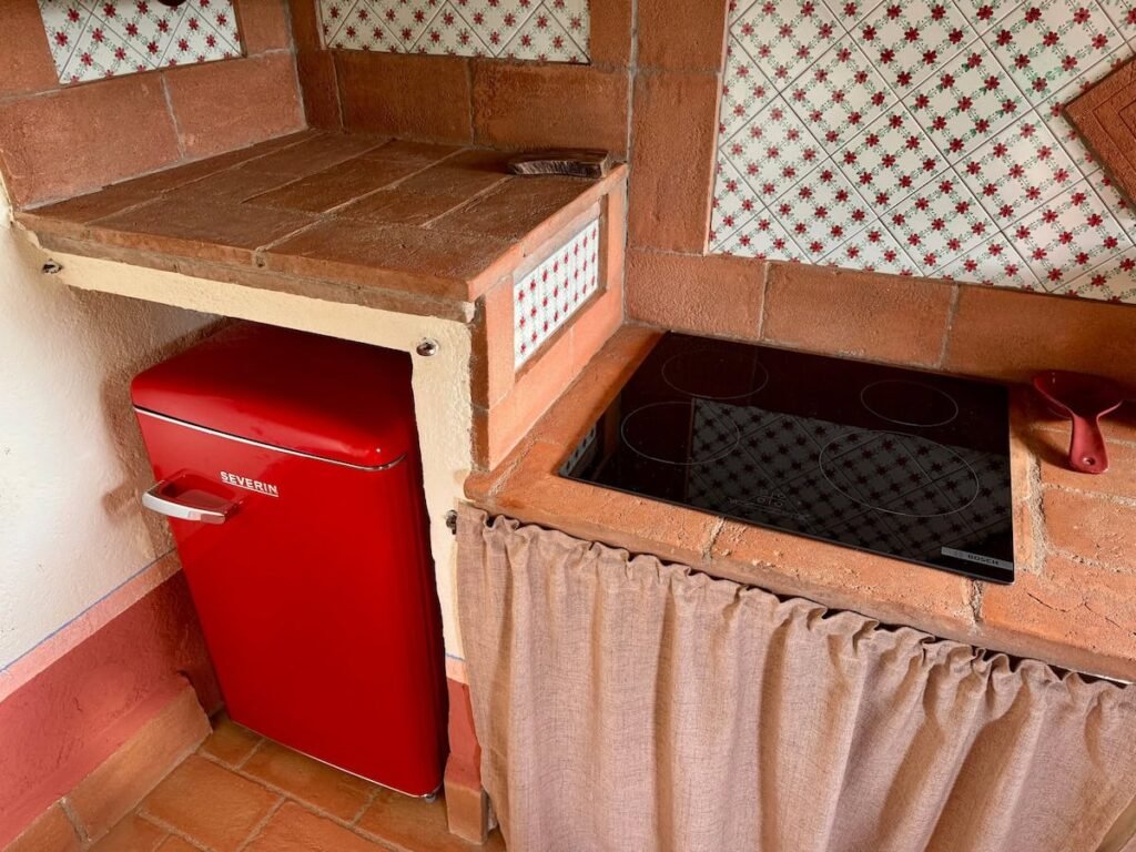 Angolo cucina con frigorifero rosso retrò e piano cottura nell'appartamento Il cavaliere, Borgo Braila, Umbria