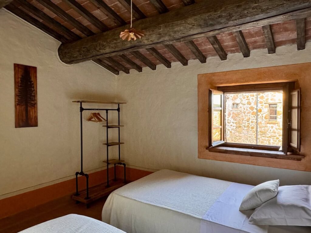 Camera da letto con letto matrimoniale e finestra sulla campagna nell'appartamento Il cavaliere, Borgo Braila, Umbria