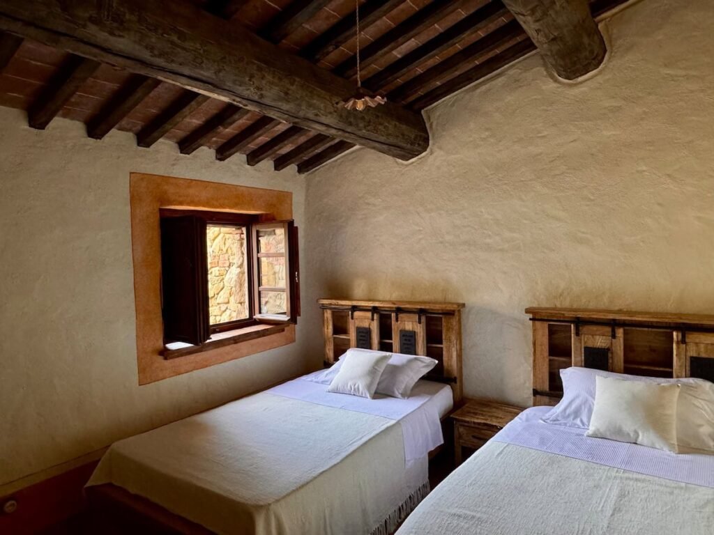 Camera da letto con soffitto a travi a vista e finestra nell'appartamento Il cavaliere, Borgo Braila, Umbria