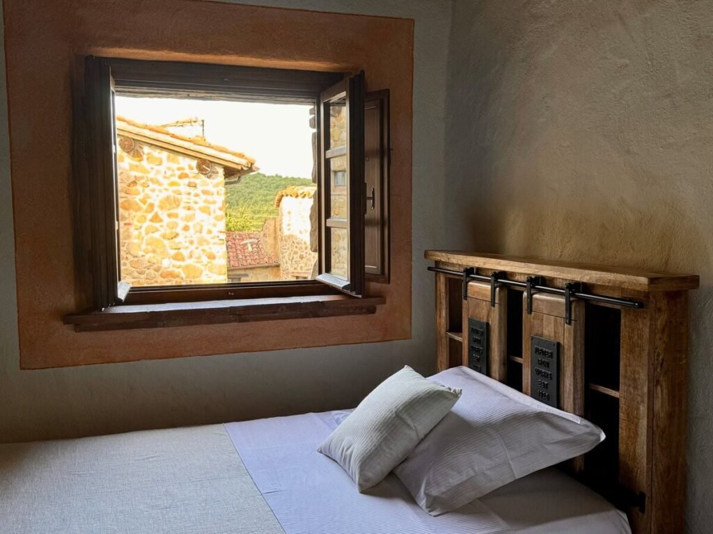 Camera da letto con finestra aperta e vista sulla pietra nell'appartamento Il cavaliere, Borgo Braila, Umbria