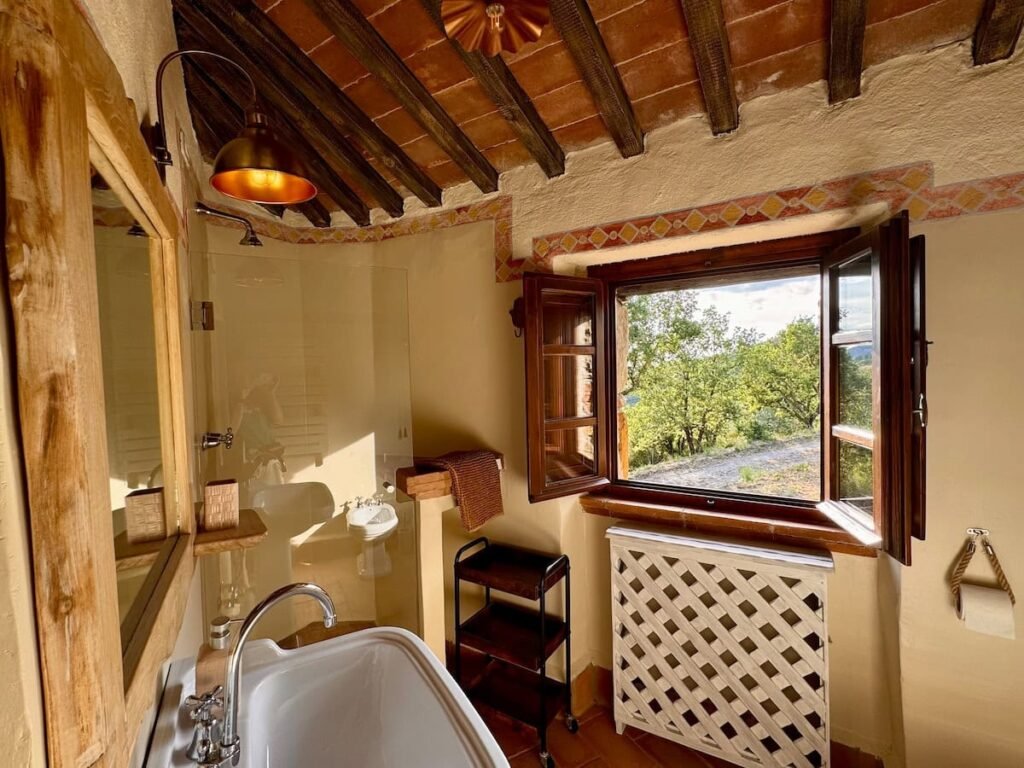 Bagno con vasca sotto una finestra panoramica nell'appartamento Il cavaliere, Borgo Braila, Umbria