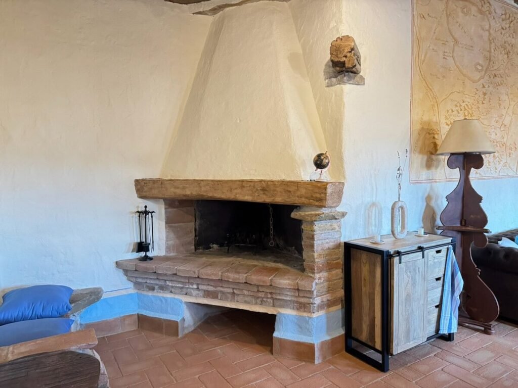 Soggiorno con camino in pietra nell'appartamento La carta, Borgo Braila, Umbria