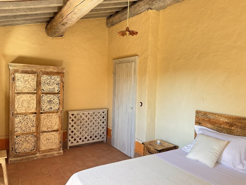 Camera da letto con testiera in legno e finestra nell'appartamento La carta, Borgo Braila, Umbria