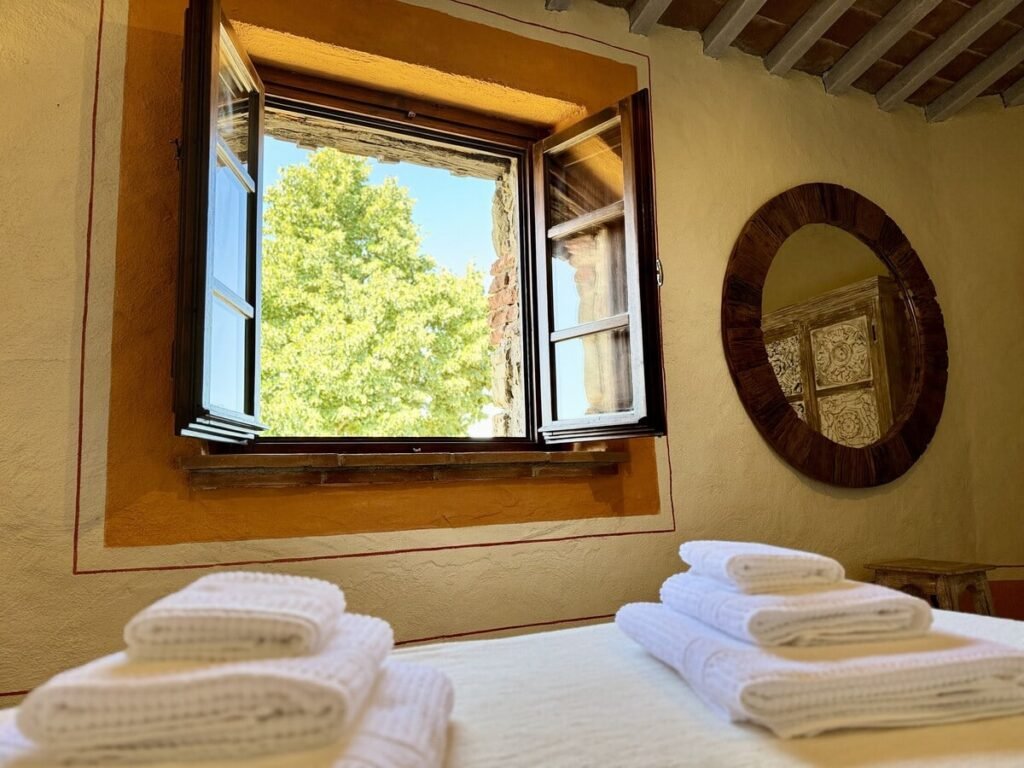 Camera da letto con finestra e specchio rotondo nell'appartamento La carta, Borgo Braila, Umbria