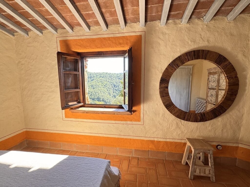 Camera da letto con specchio rotondo e finestra nell'appartamento La carta, Borgo Braila, Umbria