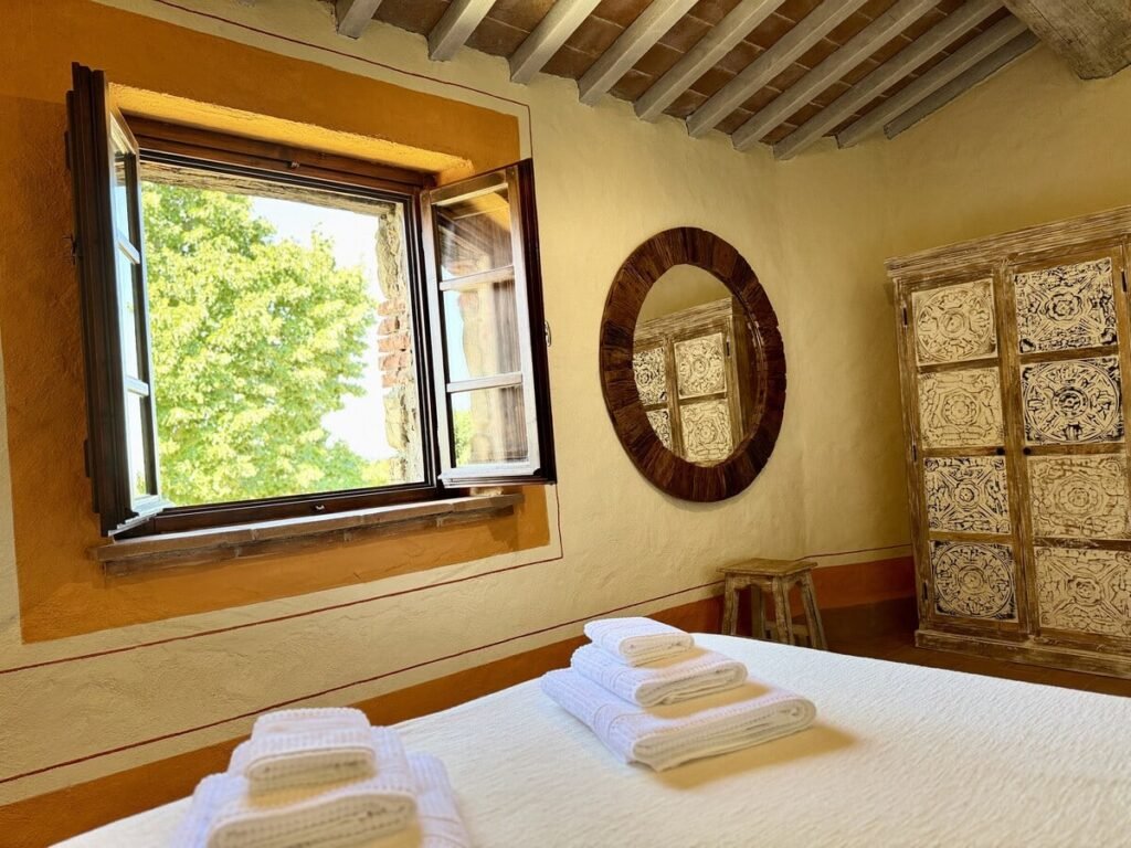 Camera da letto con finestra e specchio rotondo nell'appartamento La carta, Borgo Braila, Umbria