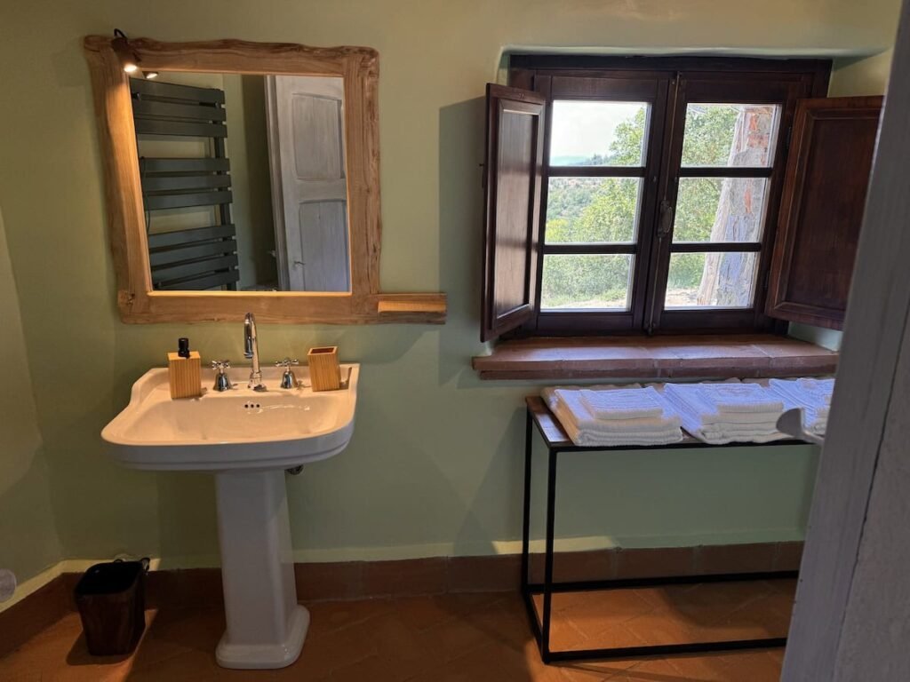 Bagno con lavabo e vista dalla finestra nell'appartamento La carta, Borgo Braila, Umbria
