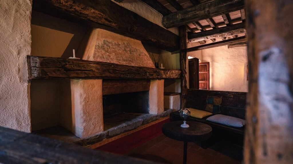 Soggiorno con travi a vista e pilastro in pietra nell'appartamento Il cardinale, Borgo Braila, Umbria