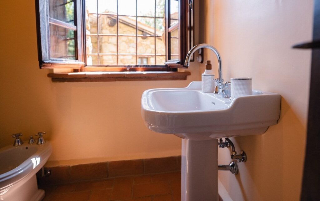 Bagno con lavabo a colonna e finestra nell'appartamento Il cardinale, Borgo Braila, Umbria