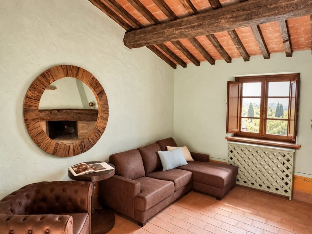 Soggiorno con divano angolare in pelle e specchio rotondo nell'appartamento La Dimora del Levante, Borgo Braila, Umbria