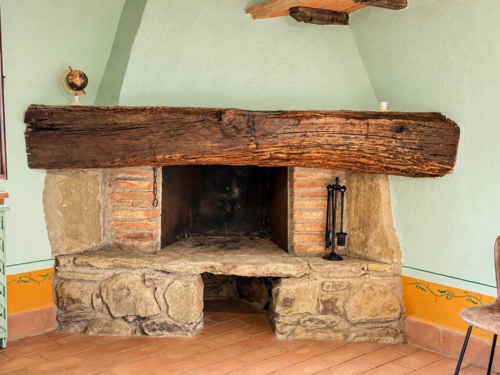 Camino in pietra con grande architrave in legno nell'appartamento La Dimora del Levante, Borgo Braila, Umbria