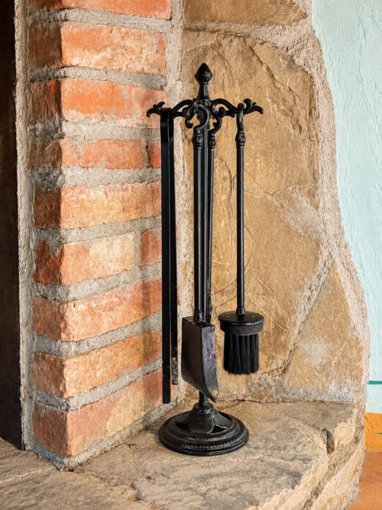 Attrezzi del camino accanto alla canna fumaria in mattoni nell'appartamento La Dimora del Levante, Borgo Braila, Umbria