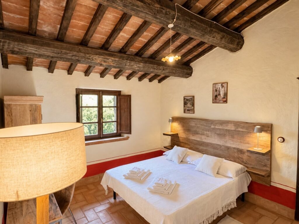 Camera da letto con letto matrimoniale e testiera in legno nell'appartamento La Dimora del Levante, Borgo Braila, Umbria