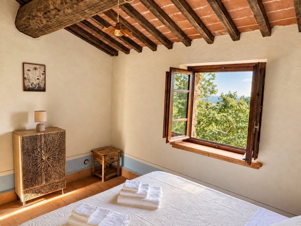 Camera da letto con finestra sulle chiome degli alberi nell'appartamento La Dimora del Levante, Borgo Braila, Umbria