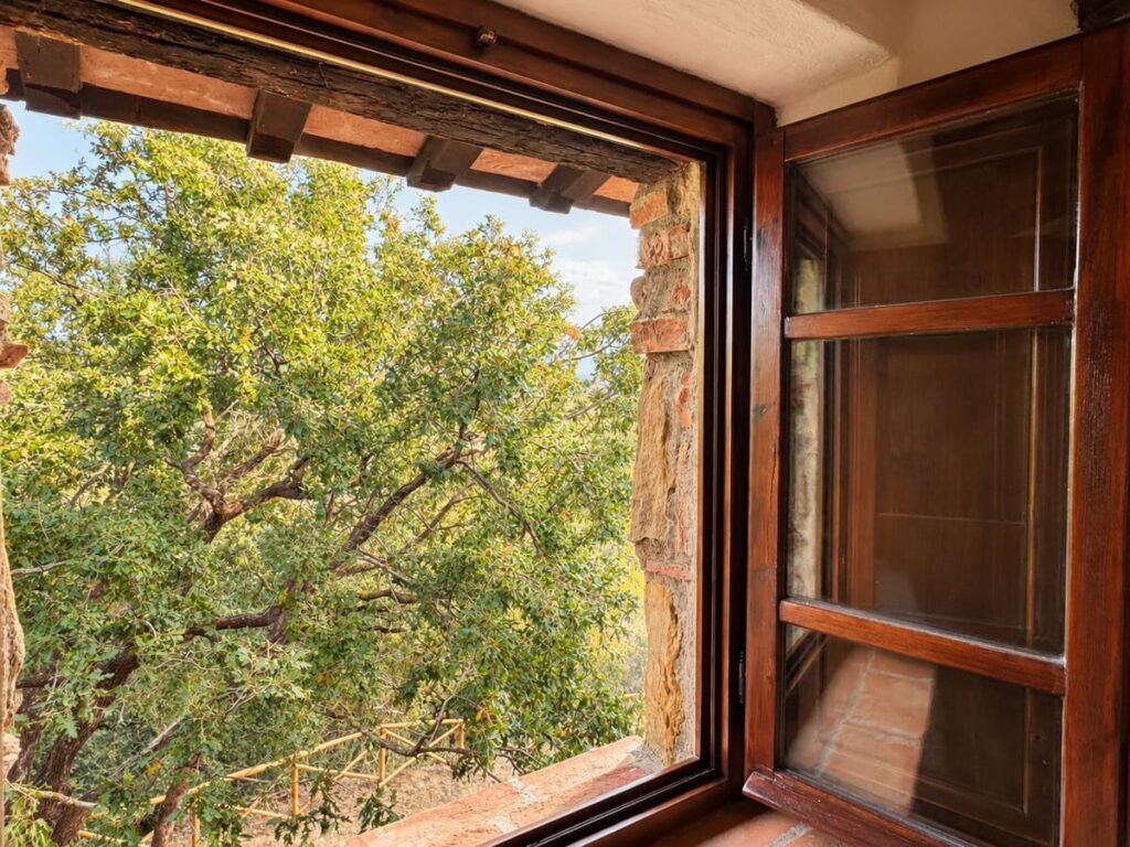 Finestra aperta con vista sulle querce nell'appartamento La Dimora del Levante, Borgo Braila, Umbria