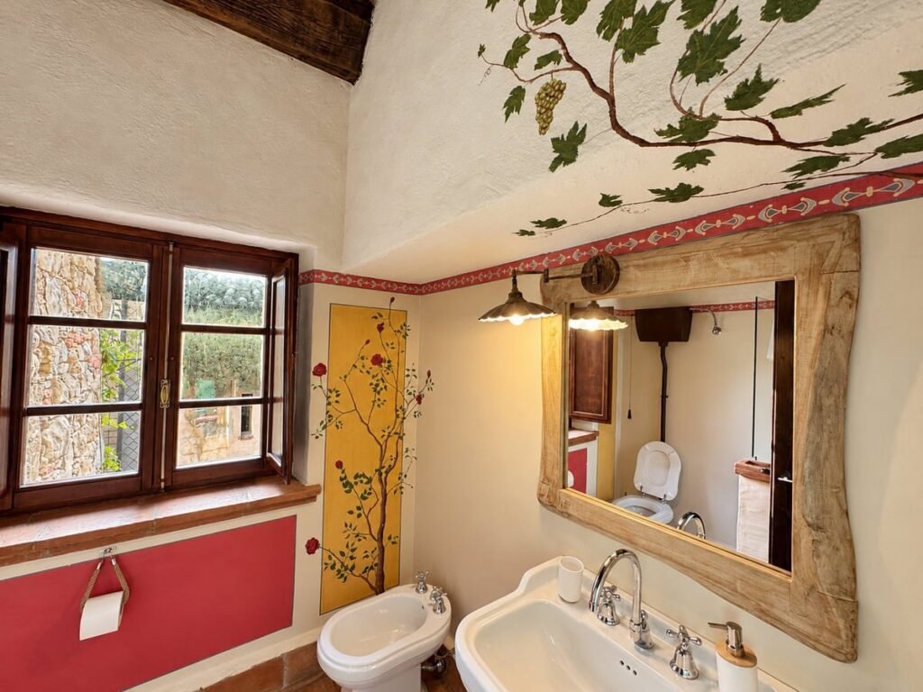 Bagno con tralcio di vite dipinto e finestra nell'appartamento La Dimora del Levante, Borgo Braila, Umbria