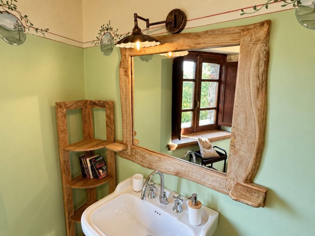 Lavabo del bagno con specchio in legno e mensola angolare nell'appartamento La Casa Nobile, Borgo Braila, Umbria